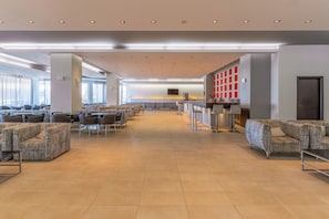A spacious lobby with seating areas, a reception desk, and a large window providing natural light. - Sol Cosmopolitan Rhodes - All inclusive (Rhodes)