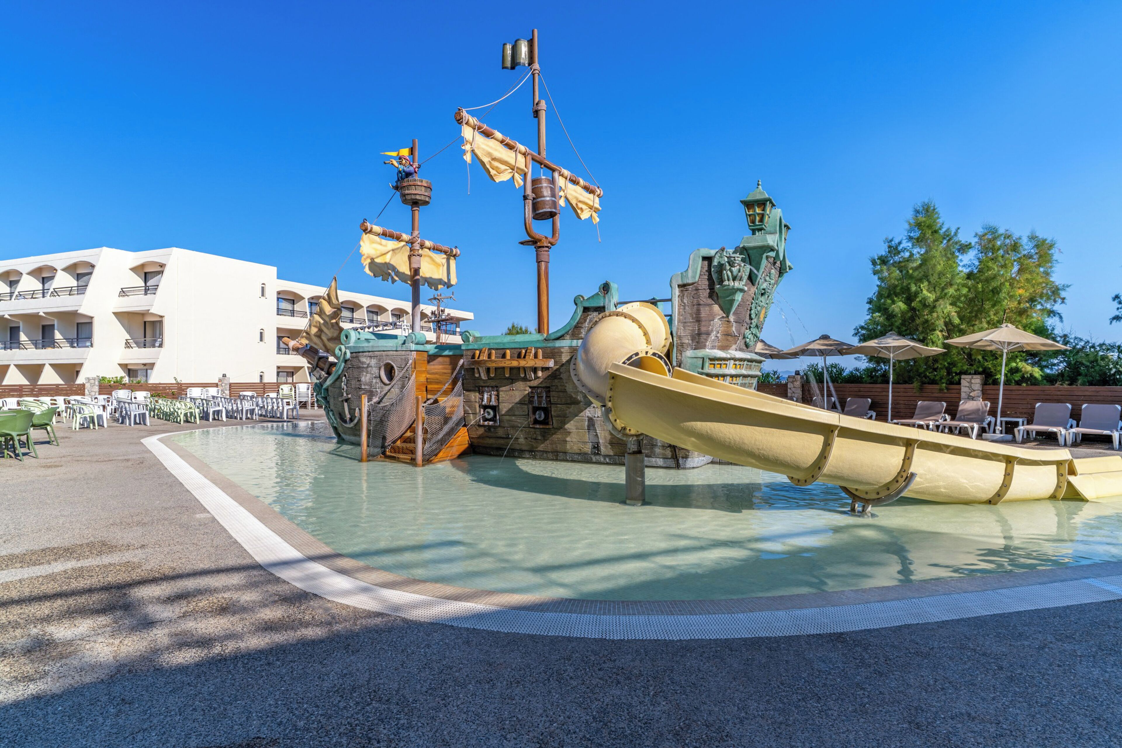 A pirate-themed water slide with a ship structure, a lifebuoy, and a flag.
