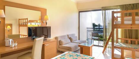 A hotel room with a bed, desk, chair, sofa, and a balcony with a view.