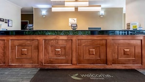 A reception desk with a 'Sleep' sign, a digital payment terminal, and a 'Welcome' mat at the entrance. - Sleep Inn & Suites Millbrook - Prattville (Millbrook)