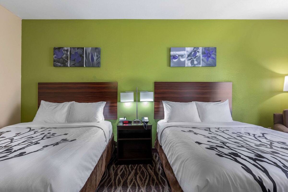 A hotel room with two beds, green walls, and artwork above the beds.