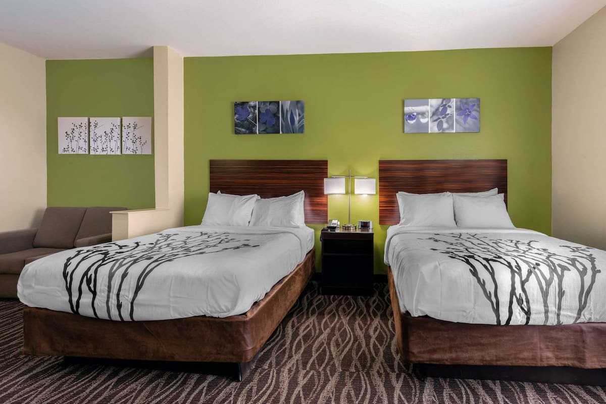 A hotel room with two beds, a sofa, and artwork on the walls.