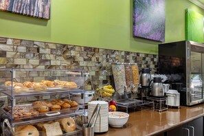 A buffet with various baked goods, a coffee station, and a refrigerator. - Sleep Inn & Suites Millbrook - Prattville (Millbrook)