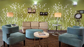 A modern living room with a green wall, two armchairs, a sofa, and a coffee table. - Sleep Inn & Suites Millbrook - Prattville (Millbrook)
