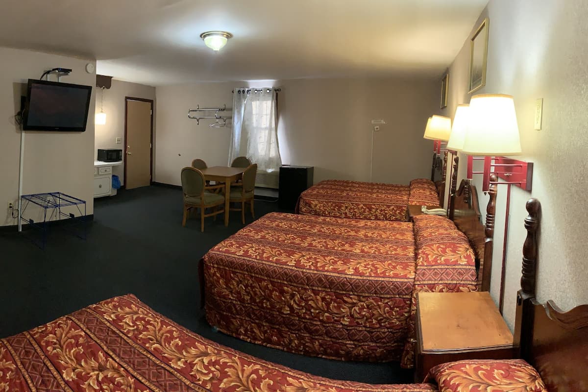 A hotel room with a large bed, a desk, a chair, a television, and a bathroom visible through an open door.