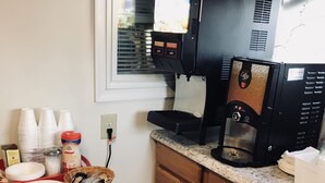 A kitchen with a coffee machine, stacked white cups, and a basket of utensils. - Dutch Motel Palmyra (Palmyra)