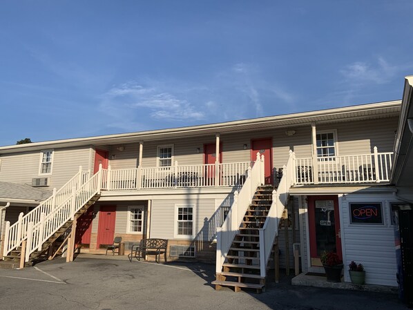 Un motel de dos pisos con una puerta roja, un balcón y una escalera.