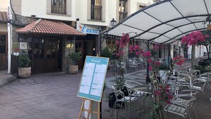 An outdoor seating area with a menu board, surrounded by metal chairs and potted plants. - Hotel Rural Spa Don Juan De Austria (Jarandilla de la Vera)