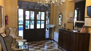 A lobby with a checkered floor, a chandelier, a reception desk, and a sign reading "SALIDA". - Hotel Rural Spa Don Juan De Austria (Jarandilla de la Vera)