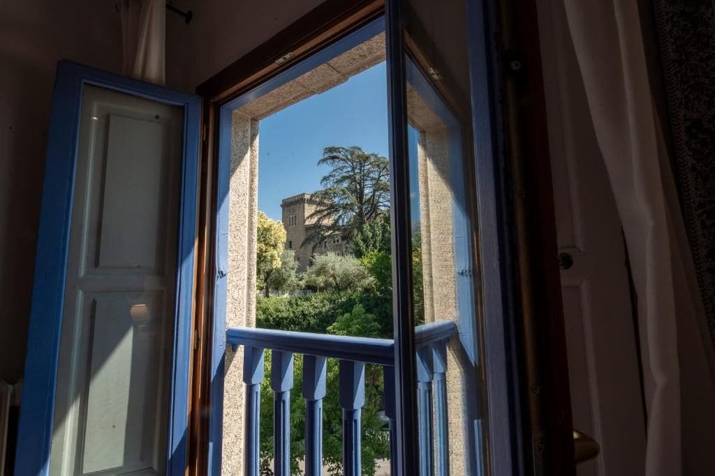 A room with a view of a building and trees through an open door.