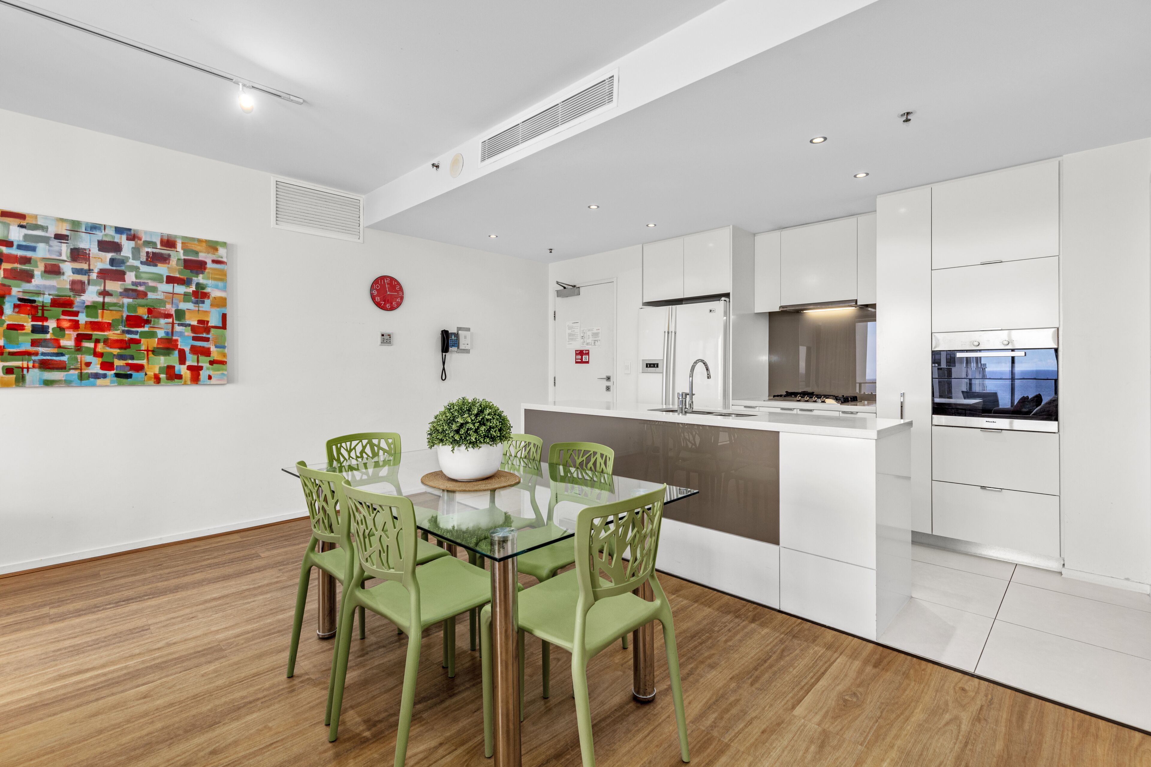 A modern kitchen with white cabinets, a stainless steel refrigerator, and a built-in oven.