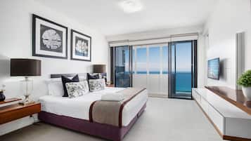 Un dormitorio moderno con una cama grande, televisión y balcón con vistas al mar.