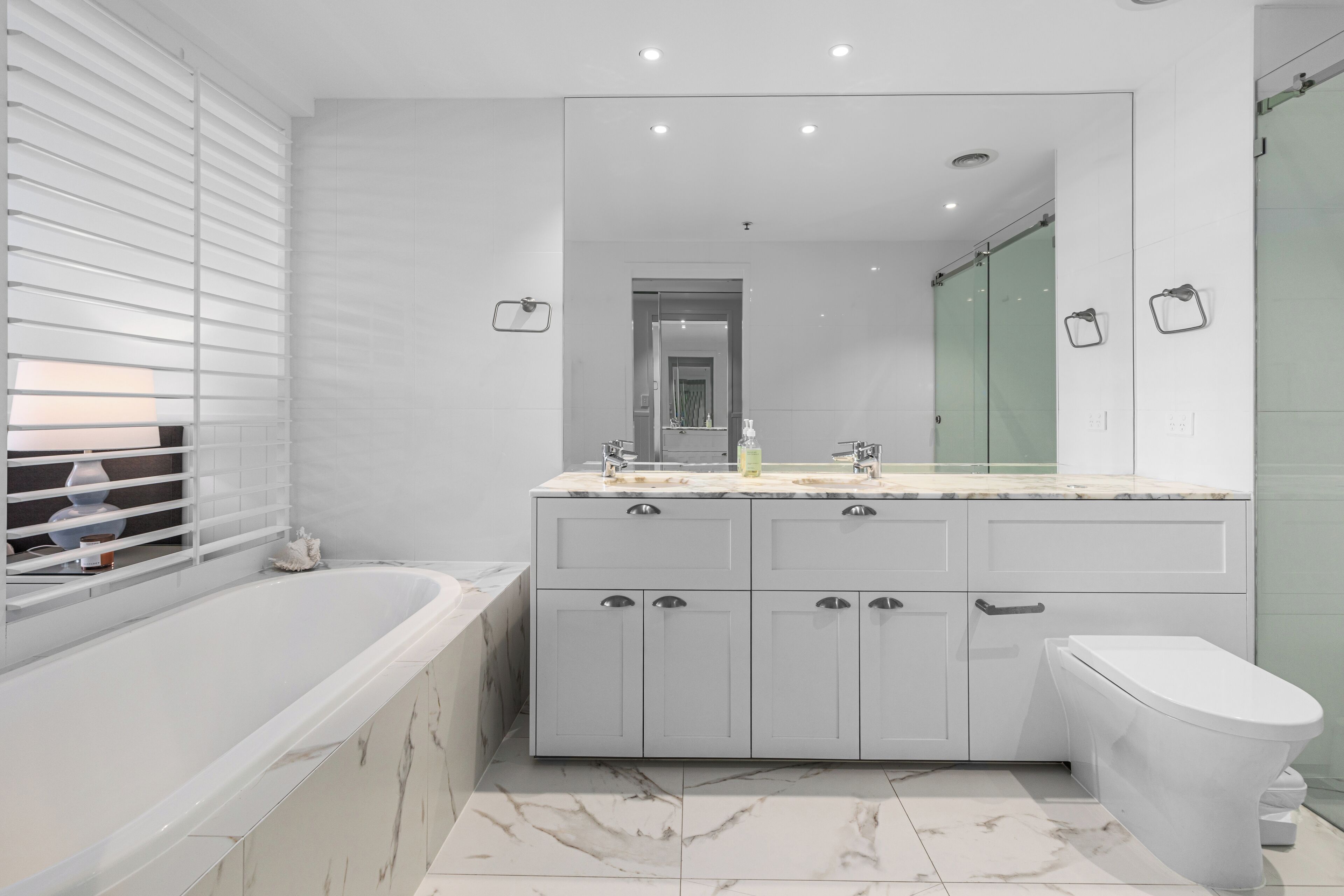 A modern bathroom with a large bathtub, a double sink vanity, and a toilet.