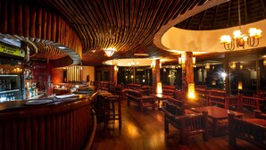 Un restaurante con interiores de madera, una zona de bar y mesas y sillas dispuestas para comer.