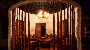 Un cuarto acogedor y circular con un banco y una mesa de madera, una araña y una puerta de madera.