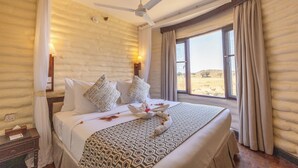 Una habitación bien equipada con una cama grande, un ventilador de techo y ventana con vistas al exterior.