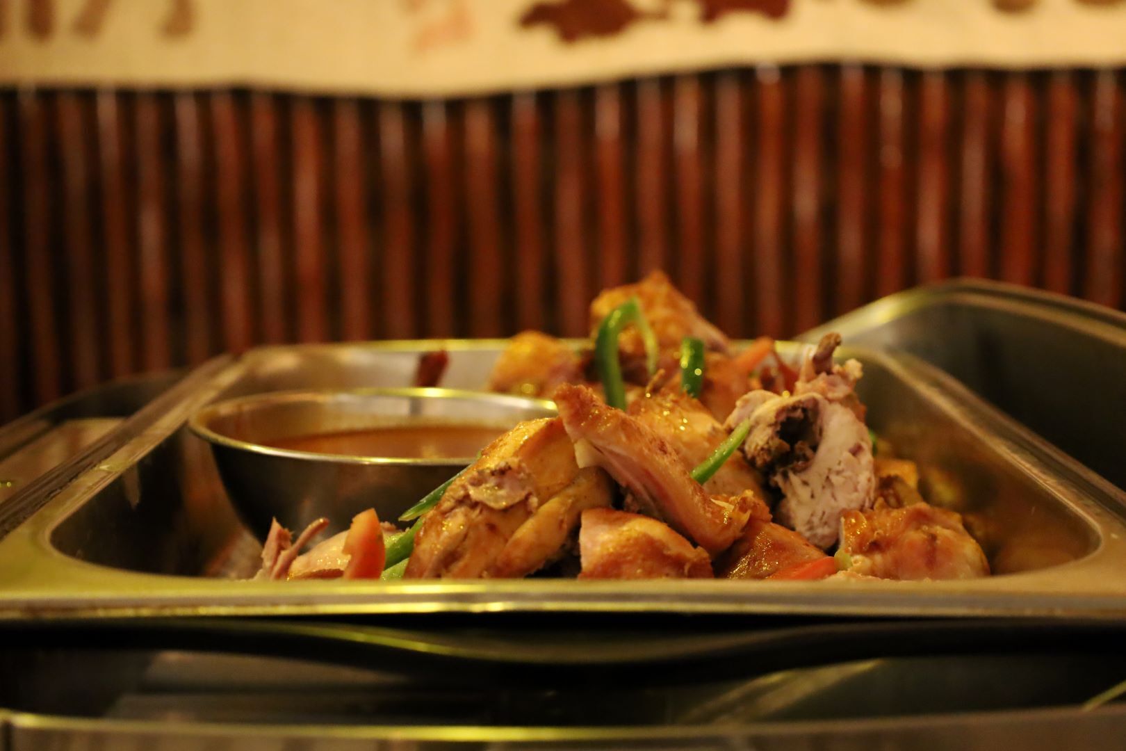 Un buffet proposant du poulet grillé et des légumes, accompagné d’une petite portion de sauce.