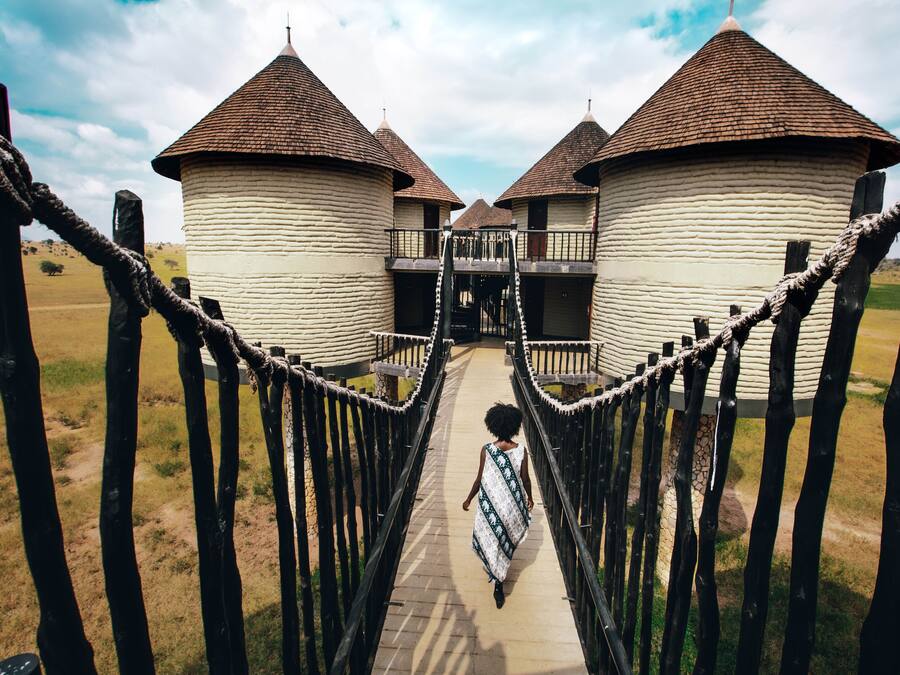A pathway leading to a row of white buildings with brown roofs.