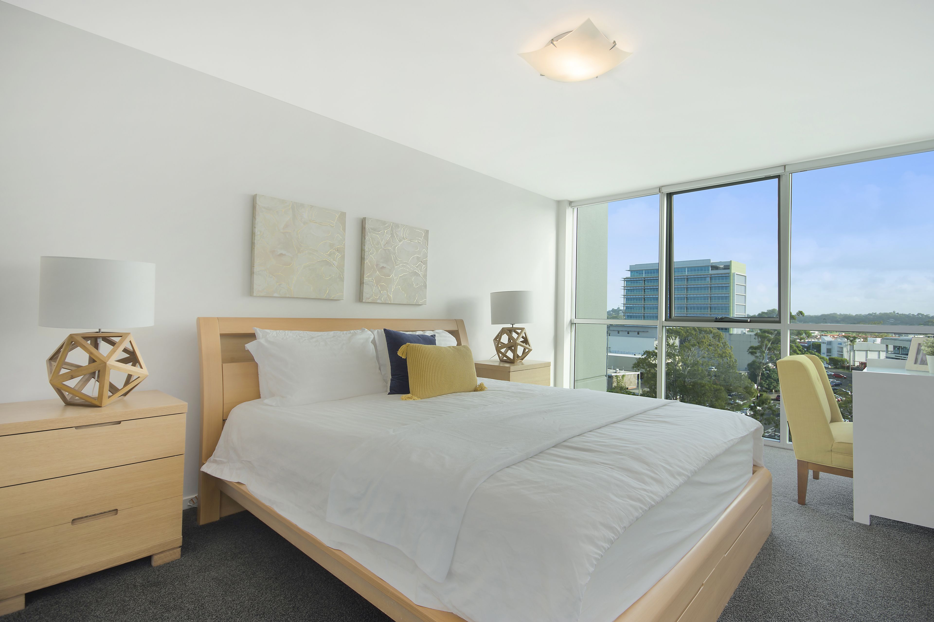 A modern hotel room with a large bed, two bedside tables, a desk, and a chair.