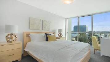 A modern hotel room with a large bed, two bedside tables, a desk, and a chair.