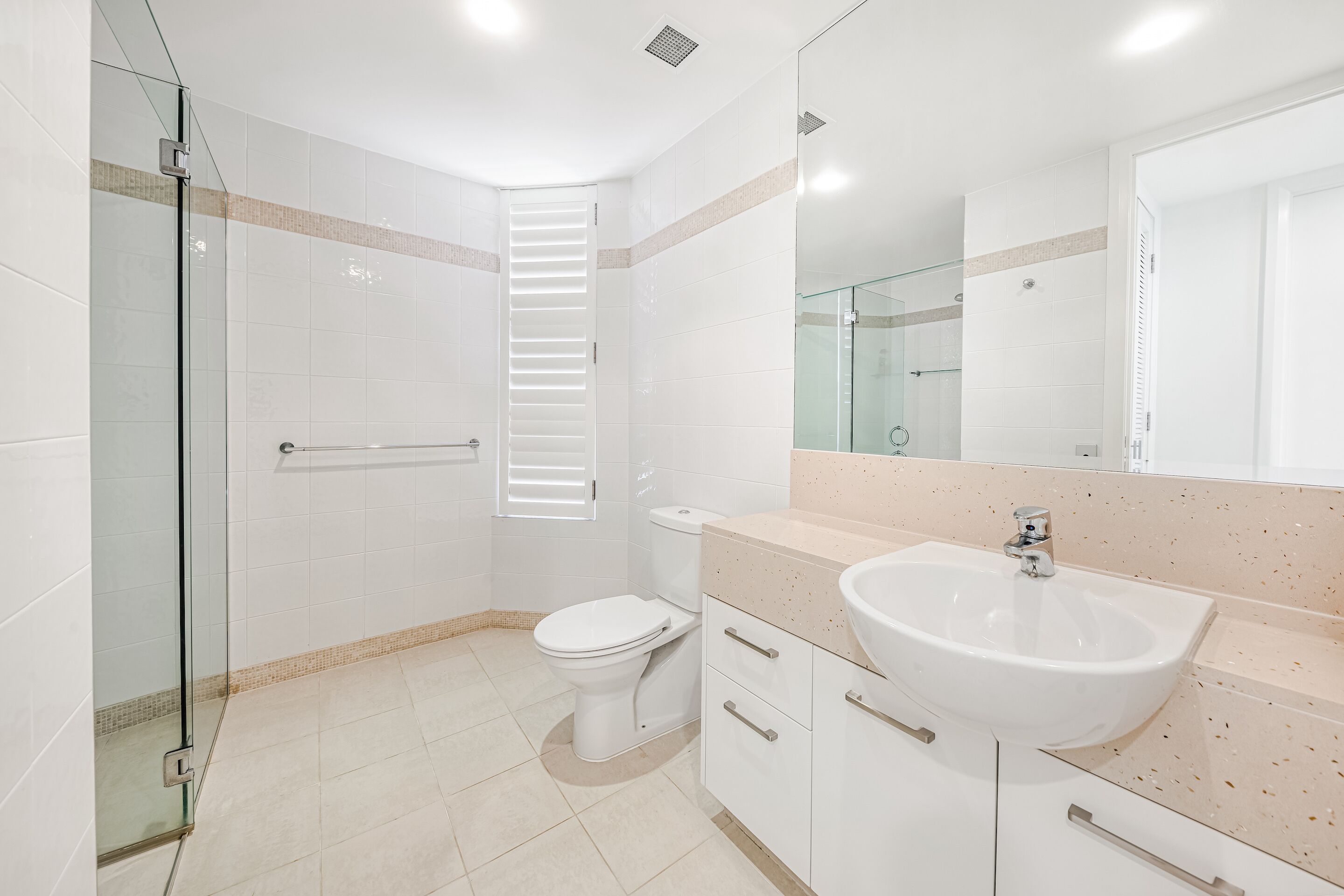 A modern bathroom with a glass shower enclosure, a toilet, a sink, and a mirror.