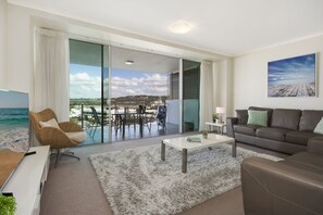 Un salon moderne doté d’une grande porte-fenêtre coulissante donnant sur un balcon avec vue sur la mer.