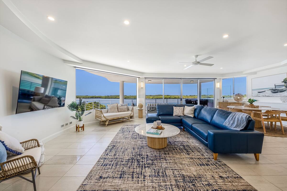 A spacious living room with a large sofa, a coffee table, and a view of the ocean.