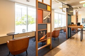 A modern interior with large windows, a reception desk, and seating areas.