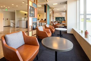 A modern lounge area with leather armchairs, a round table, and a view of the bar area.