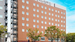 A hotel with a red brick facade, multiple windows, and a fire escape on the left.