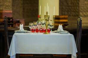 A table set for a meal with a white tablecloth, a candelabra, and red wine glasses. - Khemara Angkor Hotel & Spa (Siem Reap)