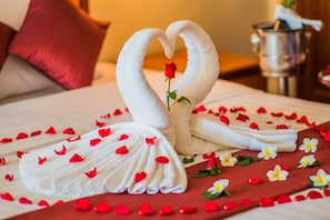 A bed with a towel arrangement in the shape of a swan, a rose, and scattered red petals. - Khemara Angkor Hotel & Spa (Siem Reap)