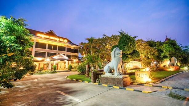 A hotel entrance with a statue of a lion, a sign reading "OUT", and a well-lit building with a sign in a foreign language. - Khemara Angkor Hotel & Spa (Siem Reap)