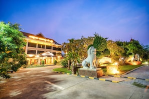 A hotel entrance with a statue of a lion, a sign reading "OUT", and a well-lit building with a sign in a foreign language. - Khemara Angkor Hotel & Spa (Siem Reap)