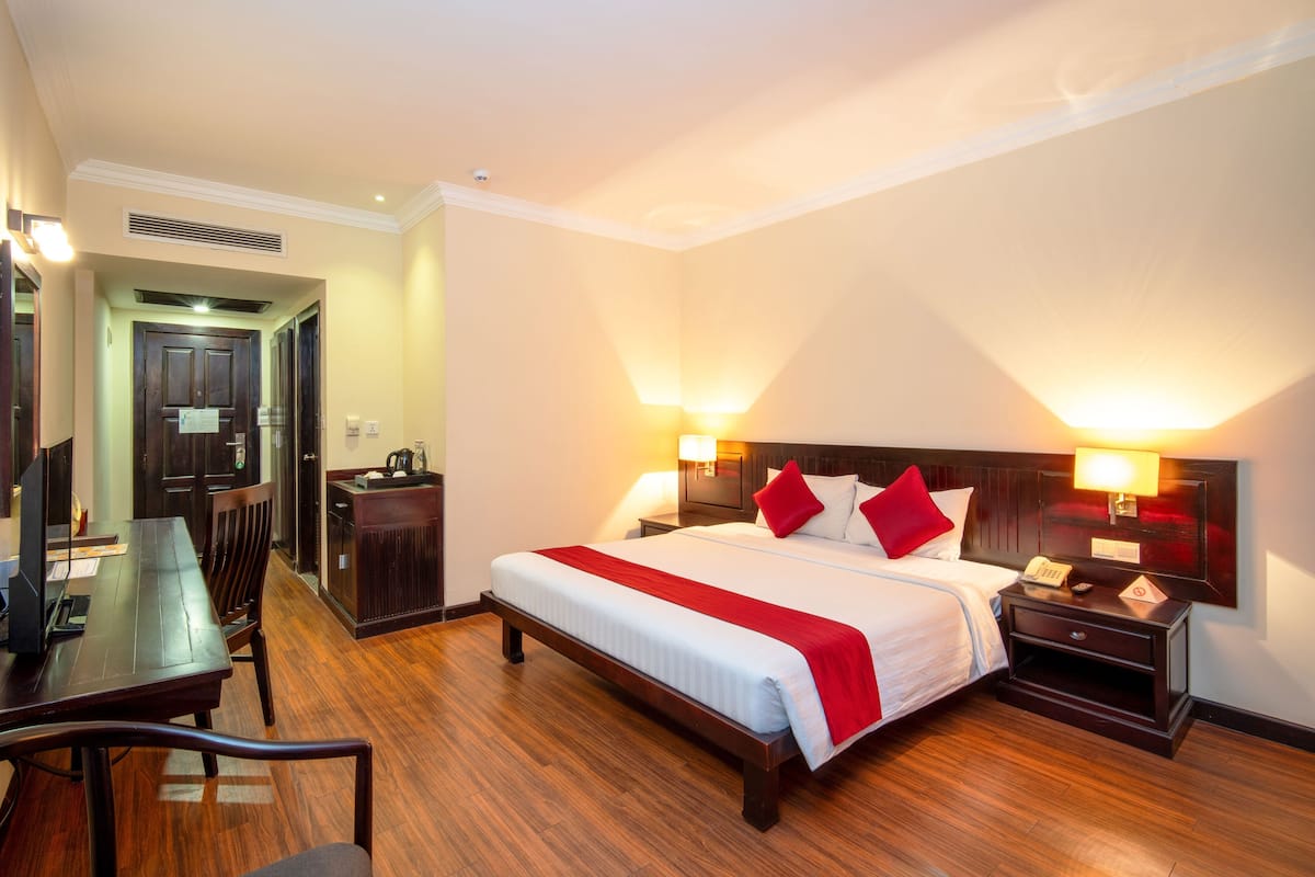 A hotel room with a large bed, bedside tables, a desk, and a chair.
