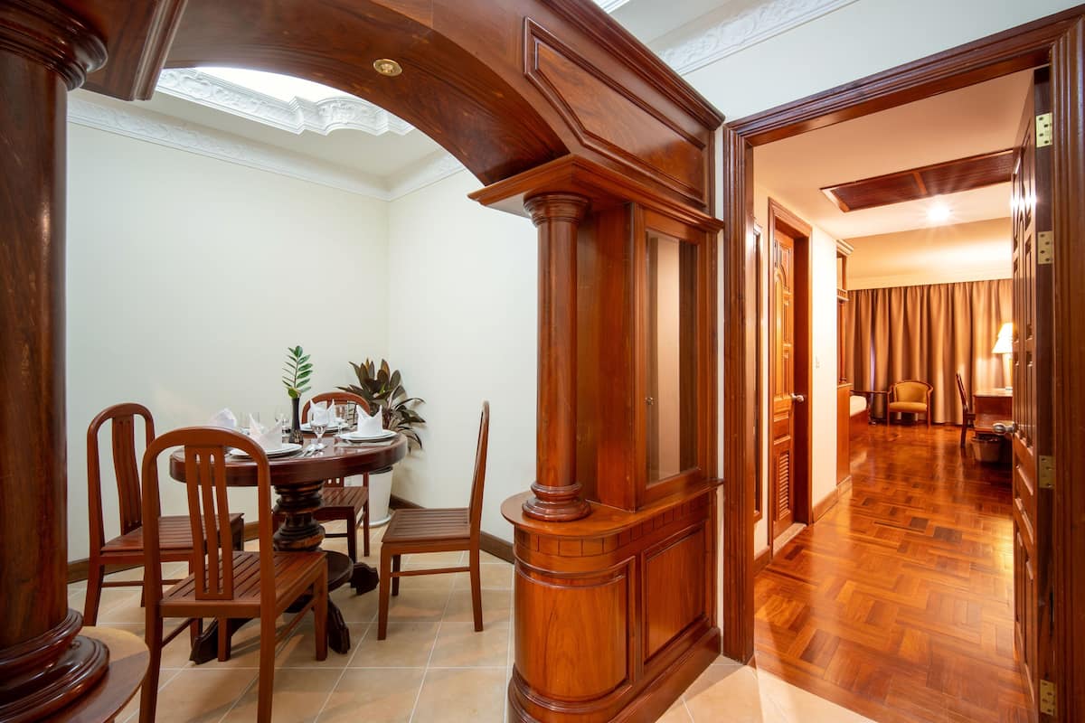 A dining area with a wooden table and chairs, a wooden column, and a hallway leading to another room.
