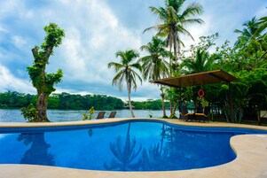 Una piscina al aire libre, sillones reclinables de piscina