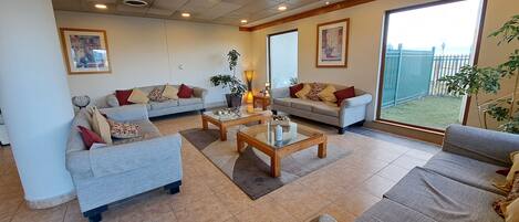 A spacious living room with two sofas, a coffee table, and a large window offering a view of a fenced yard.