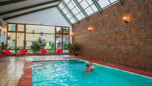 An indoor swimming pool with clear glass ceiling, red chairs, and a view of the outside building. - Diego De Almagro Punta Arenas (Punta Arenas)