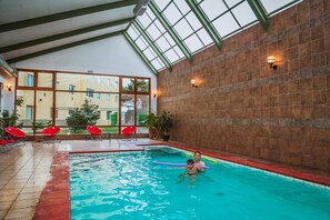 Una piscina techada, sillones reclinables de piscina