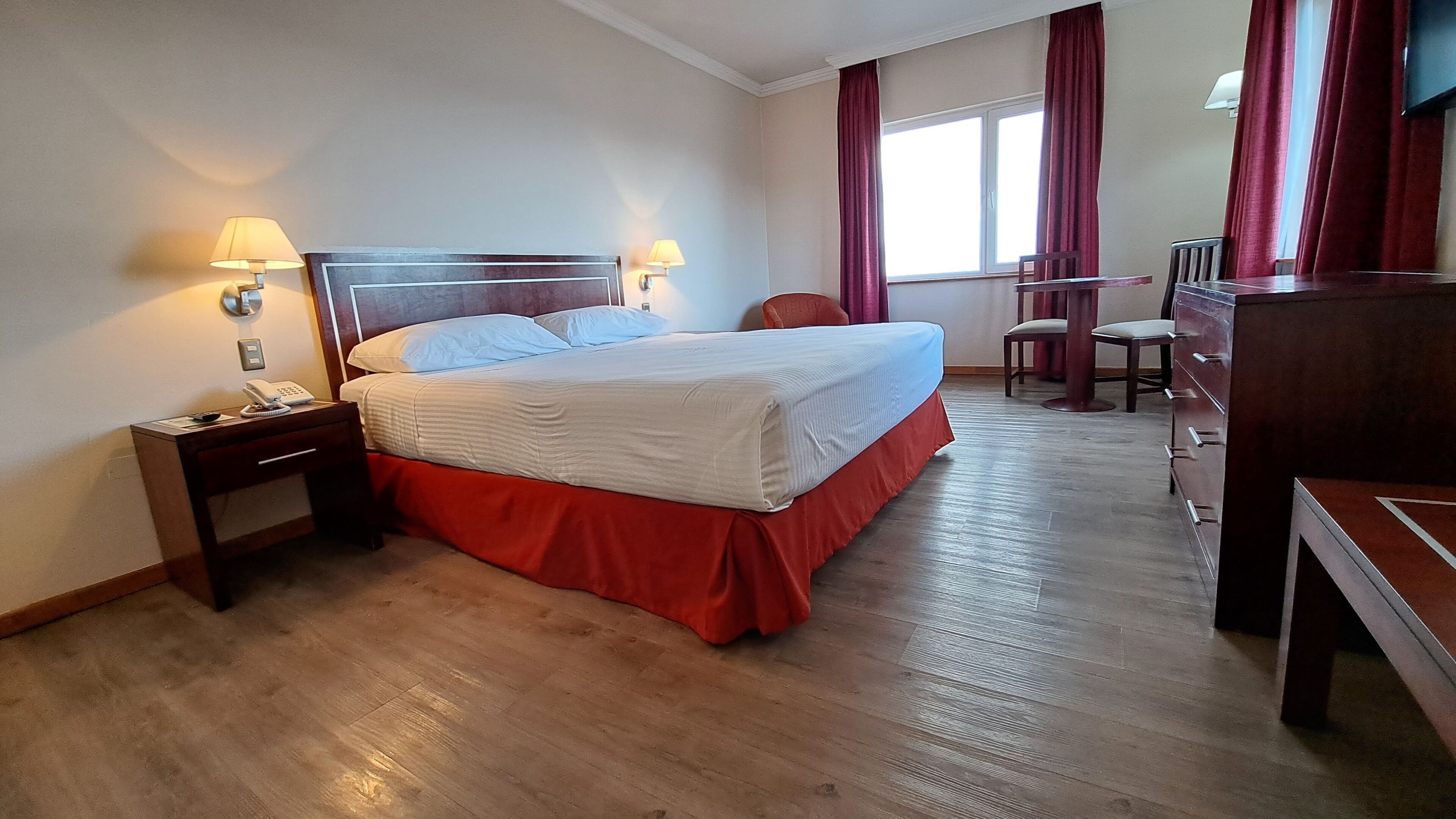 Una habitación de hotel con una cama, un escritorio, una silla y un televisor.