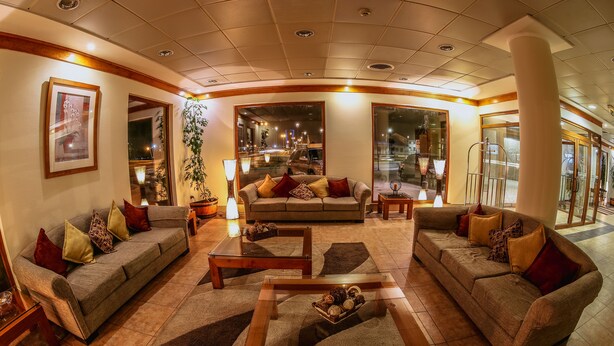 A spacious living area with a sofa set, coffee table, and a large mirror. - Diego De Almagro Punta Arenas (Punta Arenas)