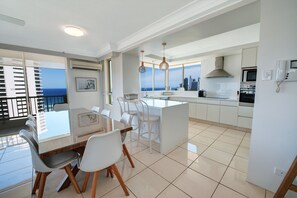 Cozinha moderna com uma ilha grande, armários brancos e vista para a cidade.
