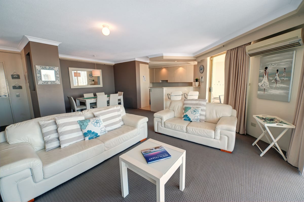 A modern living room with two white sofas, a coffee table, and a small side table.