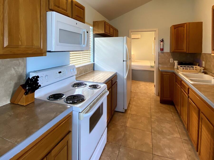 A kitchen with wooden cabinets, a white stove, a microwave, and a refrigerator.