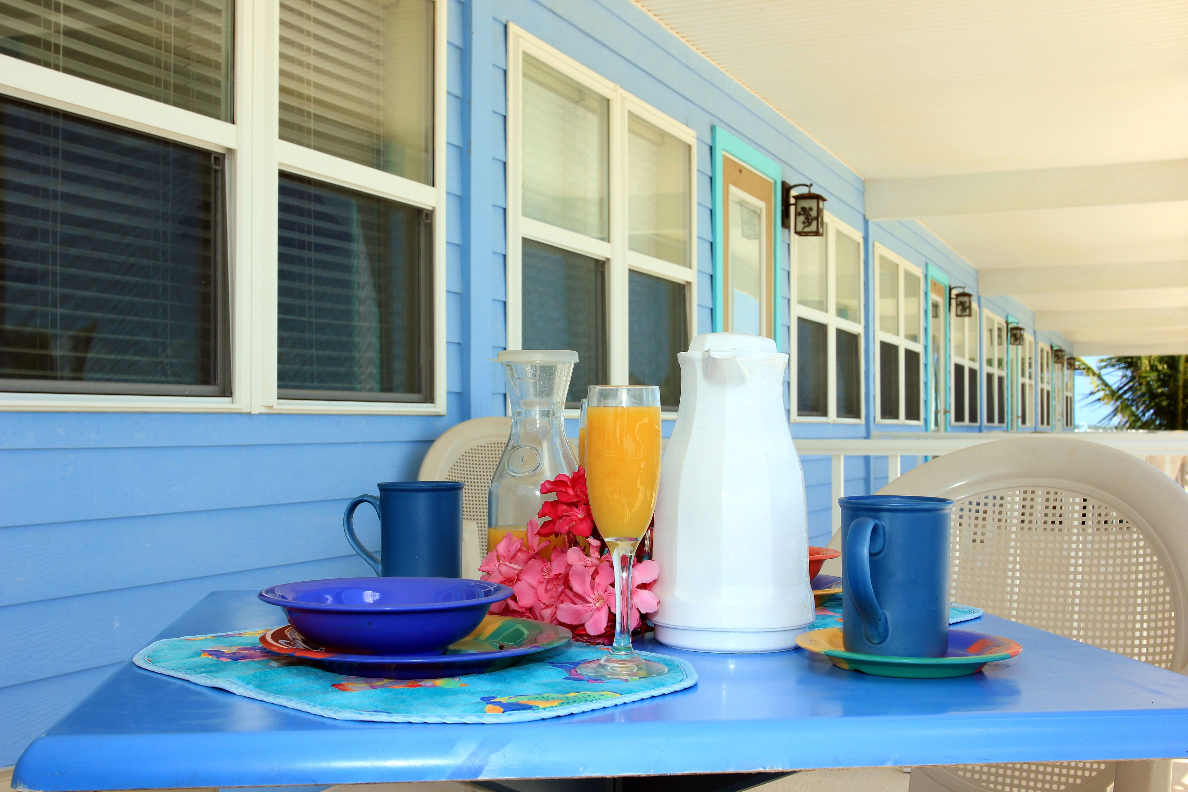 A table set with a blue bowl, a pitcher of orange juice, and a blue mug.