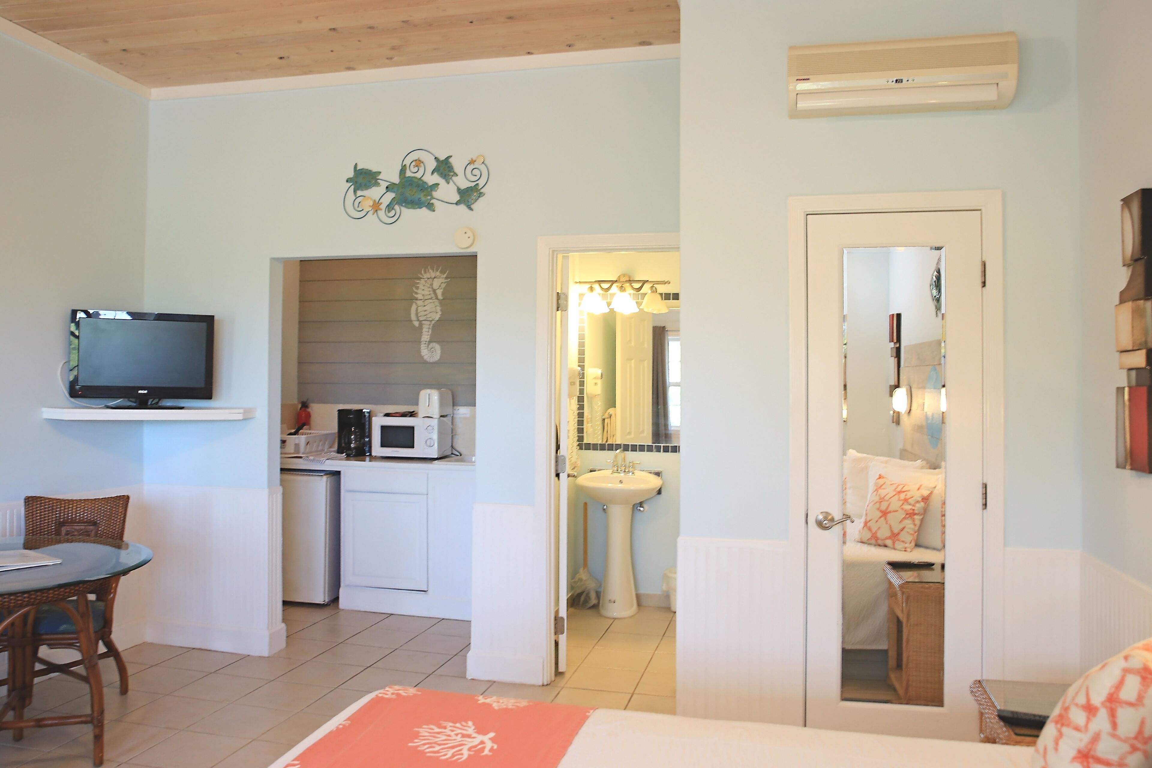 A compact room with a kitchenette, a dining area, and a bathroom.
