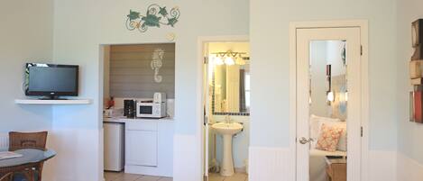 A compact room with a kitchenette, a dining area, and a bathroom.