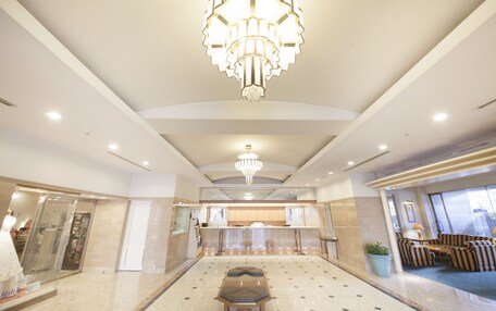 A spacious lobby with a central seating area, a reception desk, and a chandelier.