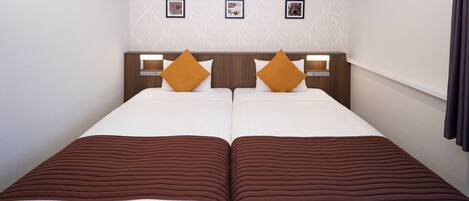 A double bed room with two pillows, a headboard with a light switch, and three framed pictures on the wall.